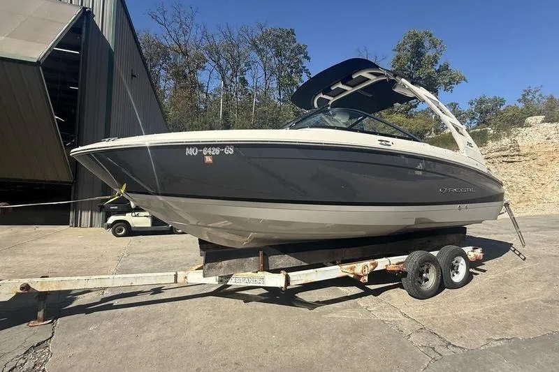 Slide: The Image of 2023 Regal LS4 Surf boat on trailer, parked outdoors near a building. - 3