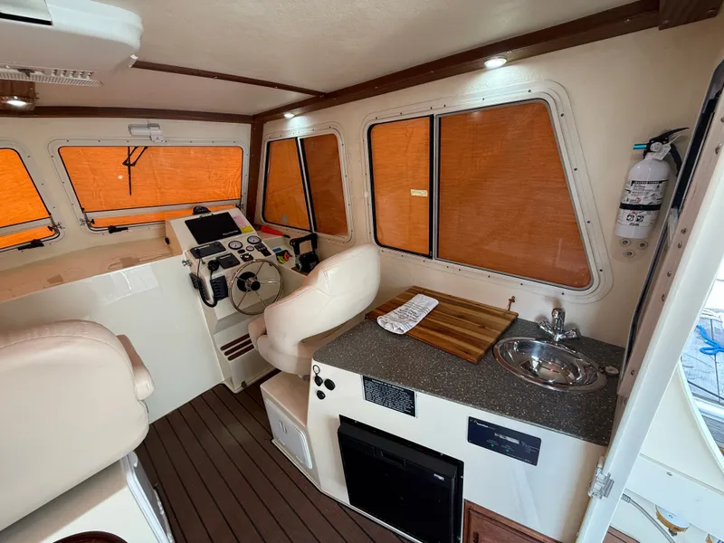Slide: The Image of Interior of a 2018 Eastern 27 Islander Hardback boat with helm and kitchenette. - 36
