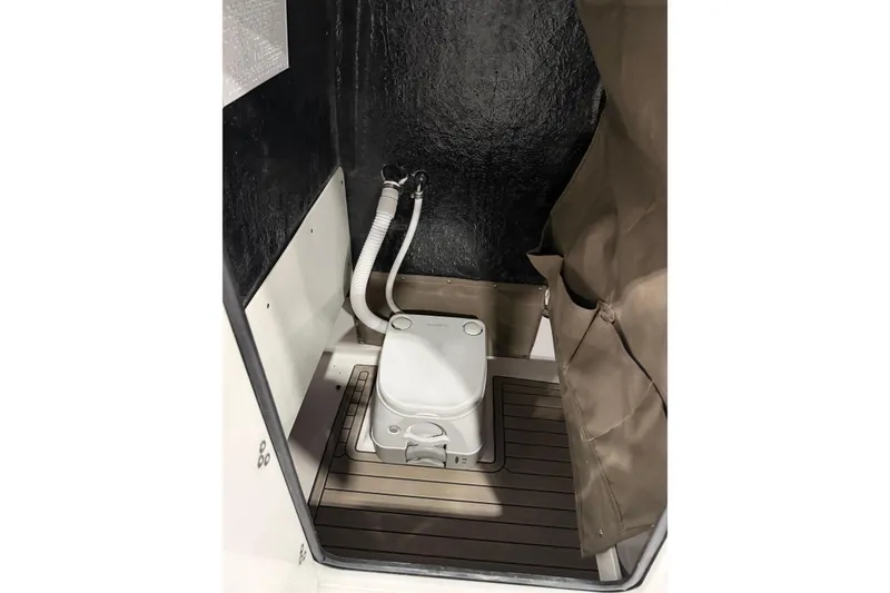 Slide: The Image of 2026 Stingray 216 CC boat interior with compact marine toilet and privacy curtain. - 8