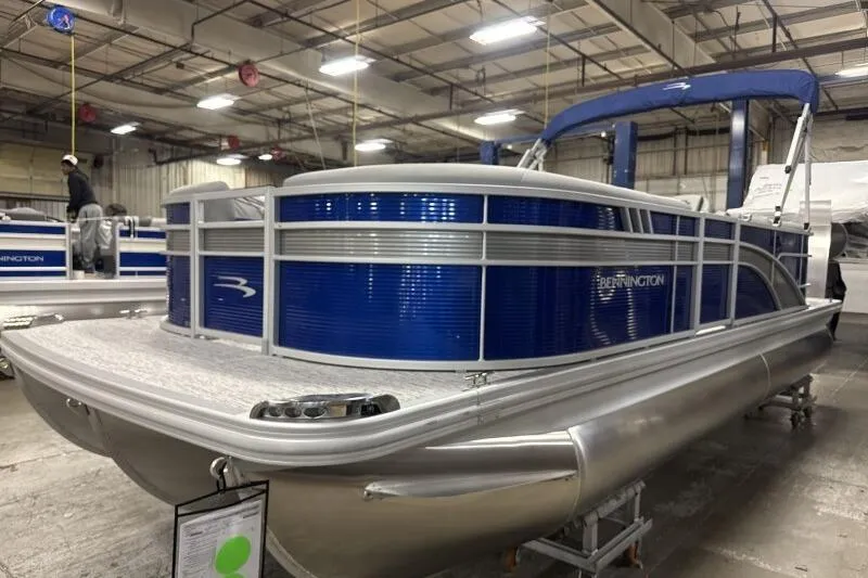 The Image of 2026 Bennington 22SXSR pontoon boat in a showroom, featuring sleek blue and silver design. - 1