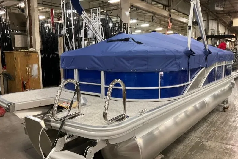 Slide: The Image of 2026 Bennington 22SXSR pontoon boat with blue cover in a warehouse setting. - 11