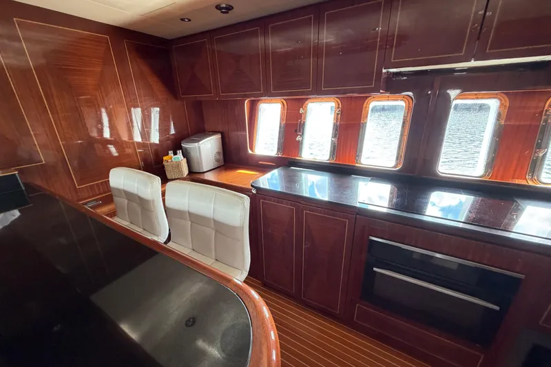 Slide: The Image of Luxurious 2004 Mangusta 72 yacht interior with elegant wood paneling and modern kitchen amenities. - 16