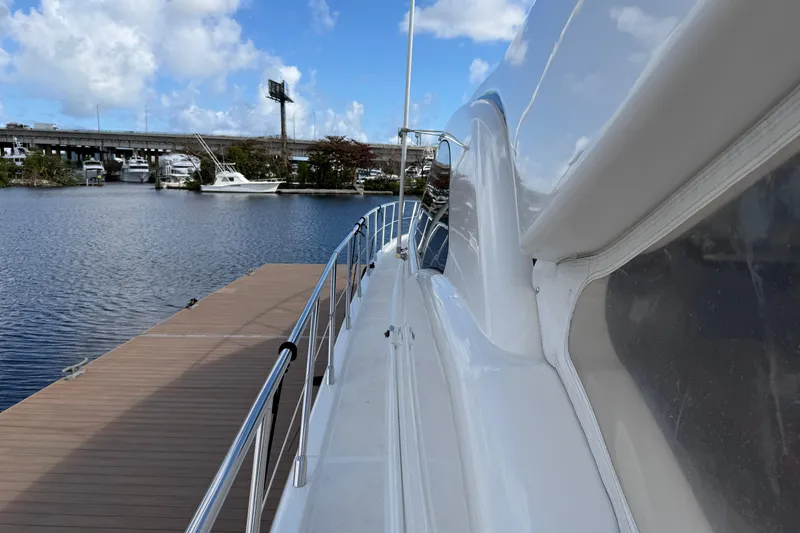 Slide: The Image of 2004 Mangusta 72 yacht docked by a serene waterfront under a blue sky. - 33
