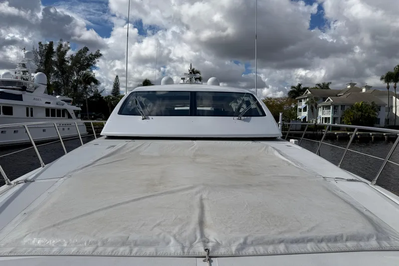 Slide: The Image of 2004 Mangusta 72 yacht docked under cloudy skies, showcasing sleek design and spacious deck. - 36