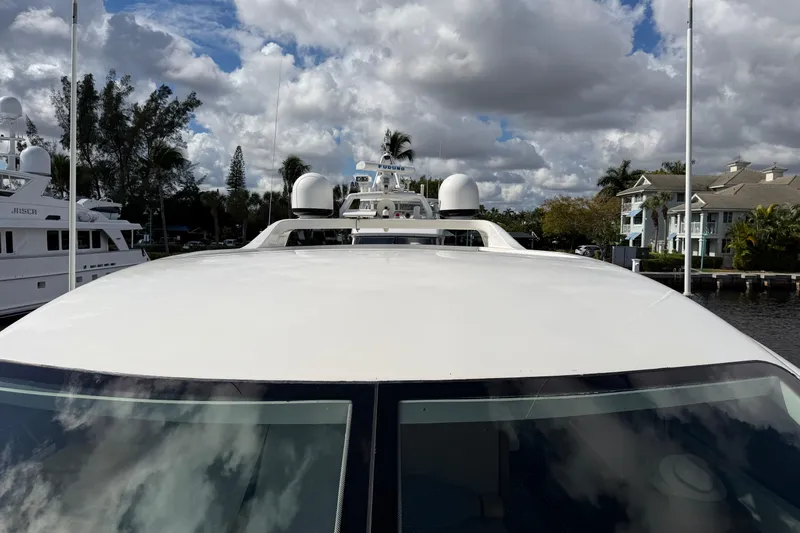 Slide: The Image of 2004 Mangusta 72 yacht docked under cloudy sky, surrounded by trees and waterfront homes. - 37