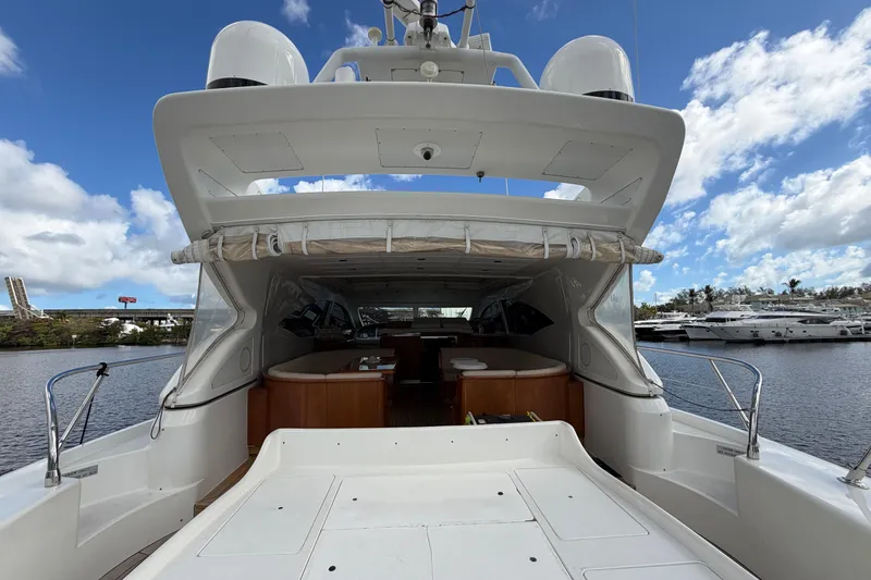 Slide: The Image of 2004 Mangusta 72 yacht docked, showcasing spacious deck and luxurious interior under a blue sky. - 7