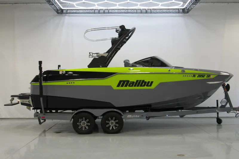 The Image of 2024 Malibu M220 boat on trailer, vibrant green and gray design in showroom. - 0