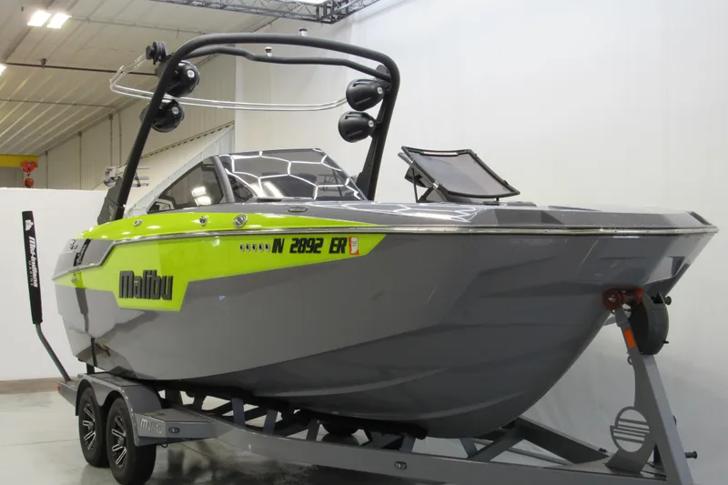 Slide: The Image of 2024 Malibu M220 boat in showroom, featuring sleek design and vibrant green accents. - 1