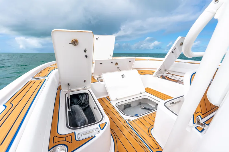 Slide: The Image of 2024 Caymas 281 HB boat deck with open storage compartments, ocean backdrop. - 12