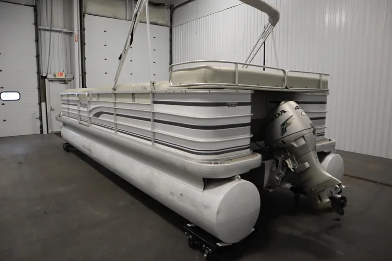 Slide: The Image of 1994 San Pan 2500 pontoon boat with Honda outboard motor in a warehouse. - 6