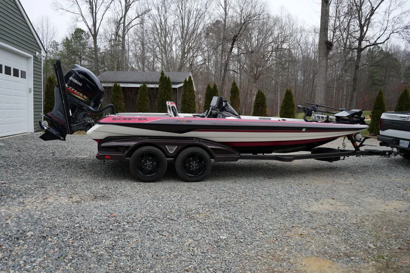 Slide: The Image of 2021 Skeeter FXR21 Apex boat on trailer, parked in a gravel driveway. - 6