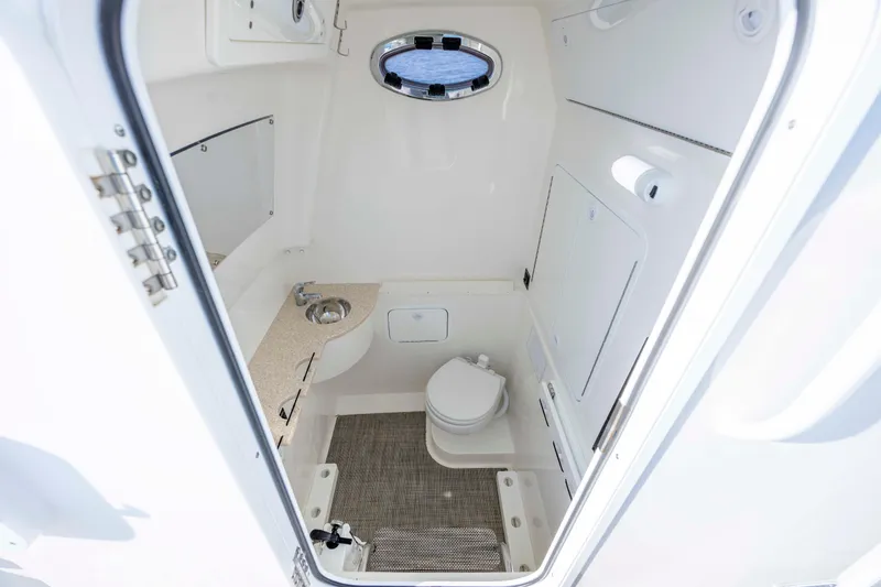 Slide: The Image of 2022 Regulator 31 boat interior bathroom with sink, toilet, and porthole window. - 13