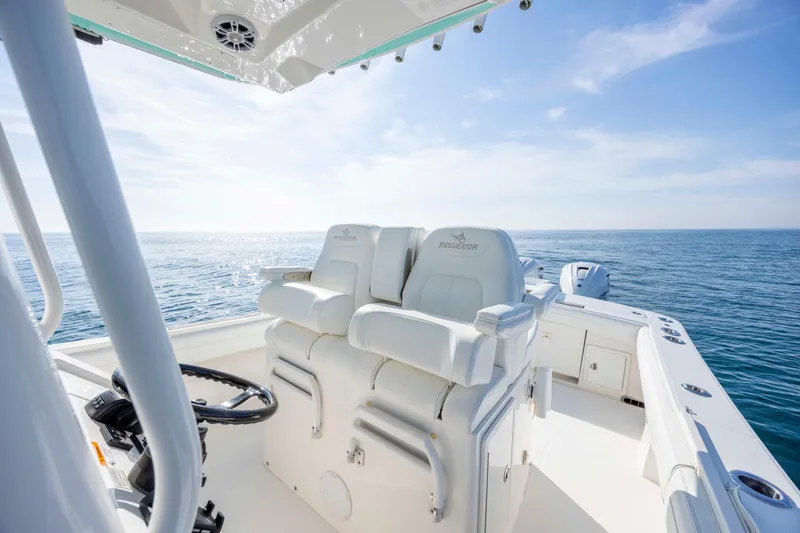 Slide: The Image of 2022 Regulator 31 boat interior with dual seats, steering wheel, and ocean view. - 16