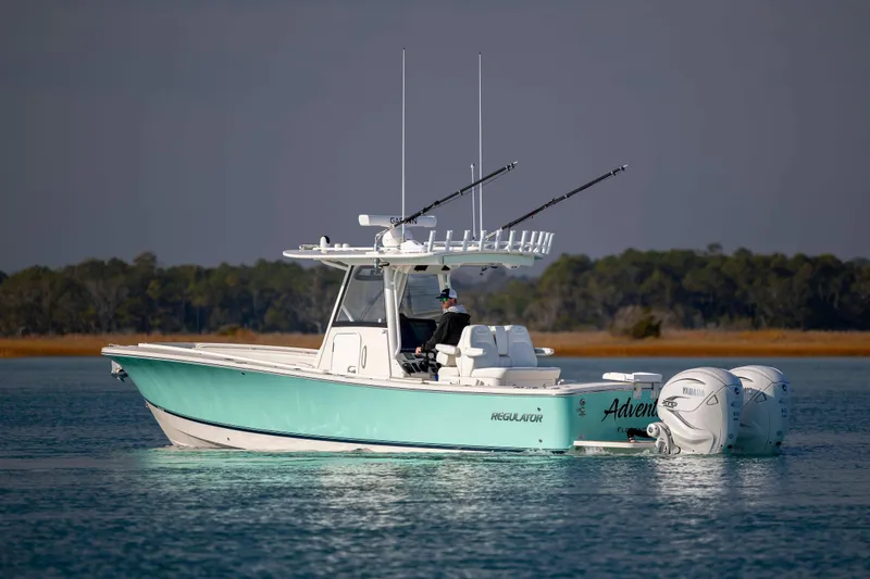 Slide: The Image of 2022 Regulator 31 boat on calm water with fishing rods and twin Yamaha engines. - 5