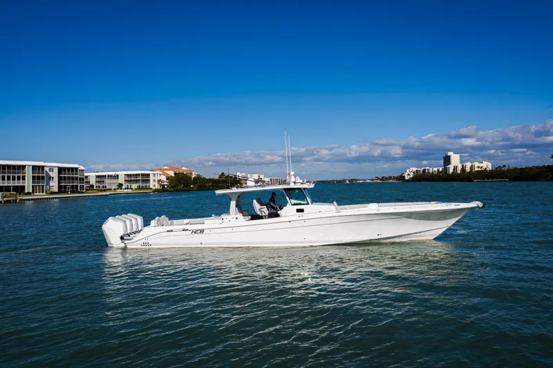 Slide: The Image of 2024 HCB 53 Sueños boat cruising on a sunny day near waterfront buildings. - 8
