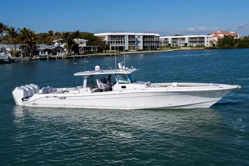 Slide: The Image of 2024 HCB 53' Suenos boat cruising on a sunny day near waterfront homes. - 0