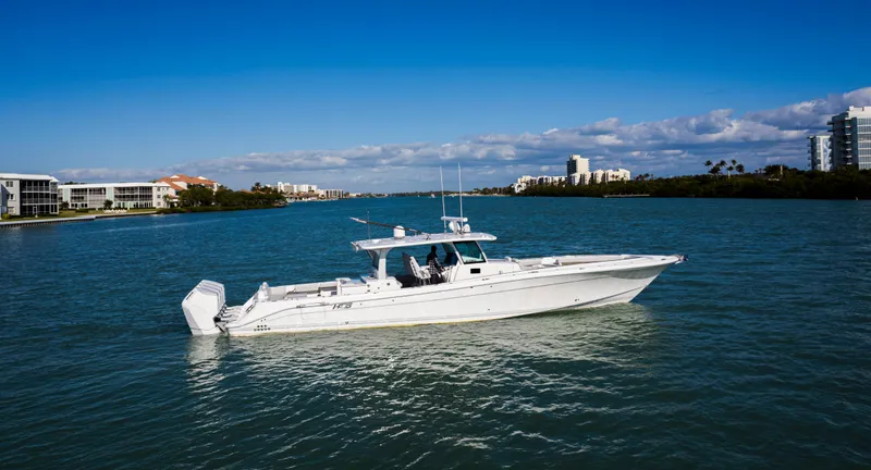 Slide: The Image of 2024 HCB 53' Suenos boat cruising on a sunny day in a coastal cityscape. - 1
