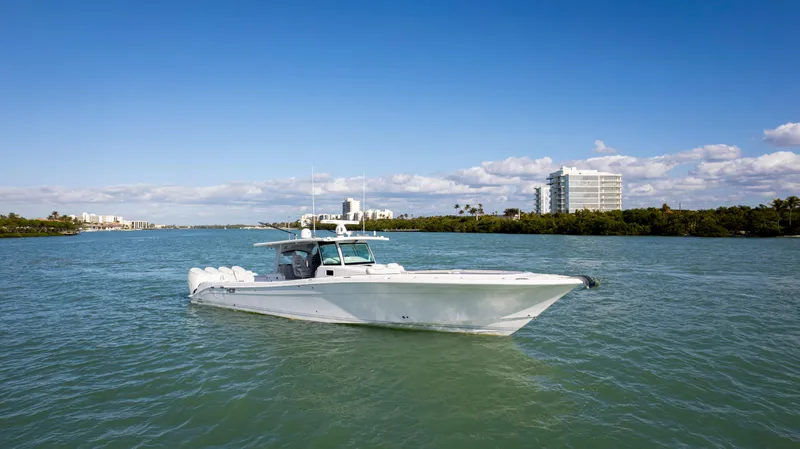 Slide: The Image of 2024 HCB 53' Suenos boat cruising on a sunny day with buildings in the background. - 3