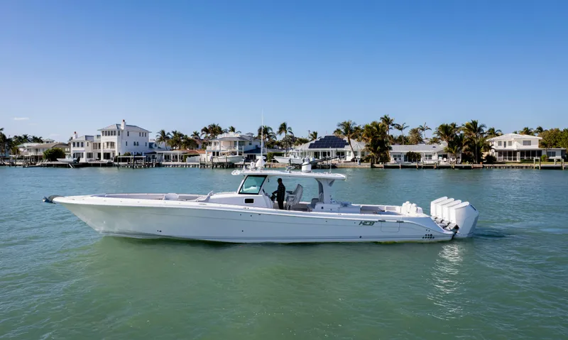 Slide: The Image of 2024 HCB 53' Suenos boat cruising on a sunny day near waterfront homes. - 5