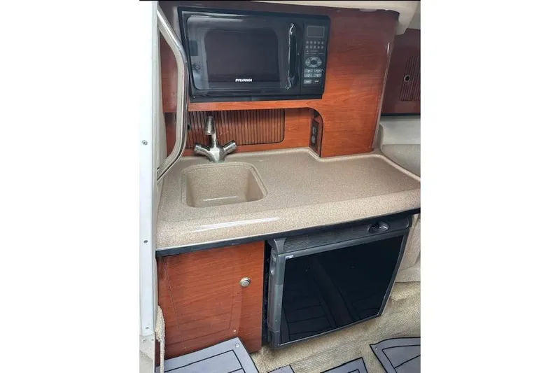 Slide: The Image of 2007 Sea Ray 290 Sun Sport cabin kitchenette with sink, microwave, and mini-fridge. - 12