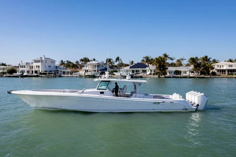 Slide: The Image of 2024 HCB 53' Suenos luxury boat cruising near waterfront homes. - 0