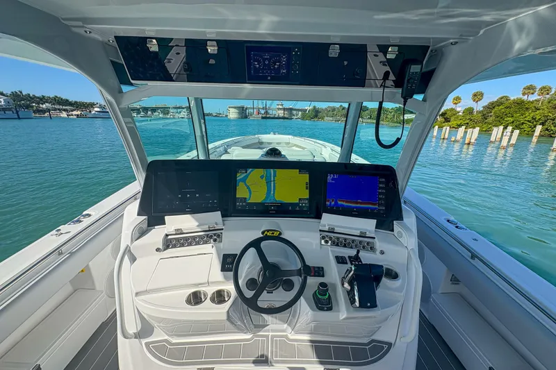 Slide: The Image of 2024 HCB 53' Suenos boat cockpit with advanced navigation displays and steering wheel. - 24
