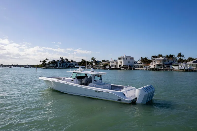 Slide: The Image of 2024 HCB 53' Suenos boat cruising near waterfront homes under clear blue sky. - 7