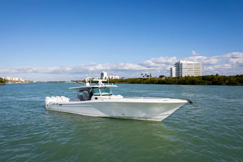 Slide: The Image of 2024 HCB 53' Suenos boat cruising on a sunny day with buildings in the background. - 9