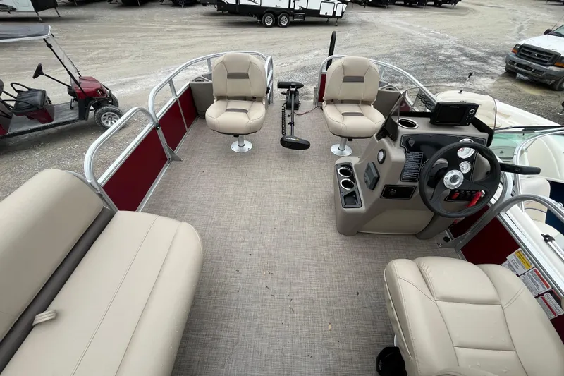 Slide: The Image of 2025 Sun Tracker Bass Buggy 18 DLX pontoon boat interior with beige seating and steering console. - 2