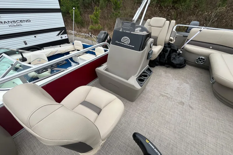 Slide: The Image of 2025 Sun Tracker Bass Buggy 18 DLX interior with seating and console, parked near RV. - 7