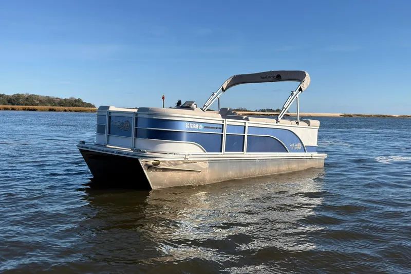 Slide: The Image of 2021 SunCatcher Select 20C pontoon boat on calm water under clear blue sky. - 2