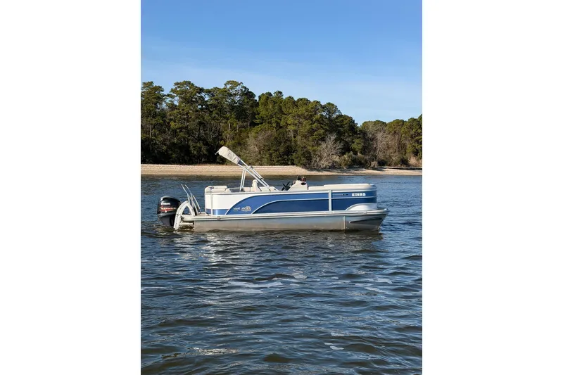 Slide: The Image of 2021 SunCatcher Select 20C pontoon boat on a serene lake with forested shoreline. - 3