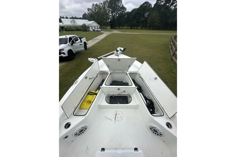 Slide: The Image of 2022 BlackJack 256 Bay boat with open storage compartments, parked near a white truck. - 8