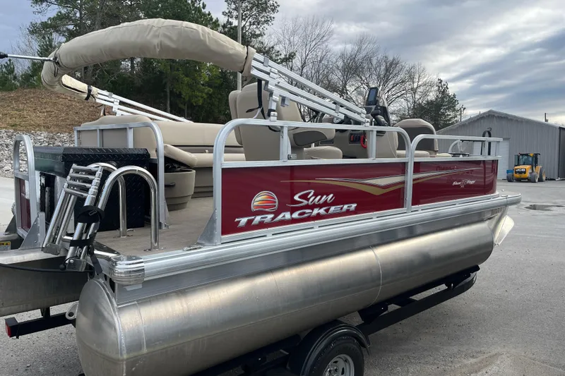 Slide: The Image of 2025 Sun Tracker Bass Buggy 16 XL Select pontoon boat on trailer, parked outdoors. - 8