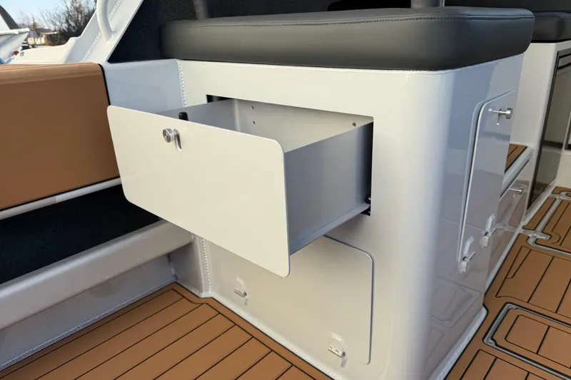 Slide: The Image of Open storage compartment on 2026 Makaira Gen3 26 Outboard boat with cushioned seating. - 12