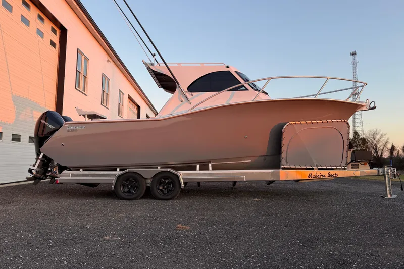 Slide: The Image of 2026 Makaira Gen3 26 Outboard boat on trailer near building at sunset. - 3