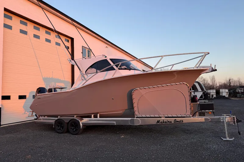 Slide: The Image of 2026 Makaira Gen3 26 Outboard boat on trailer, parked outside a large garage. - 4