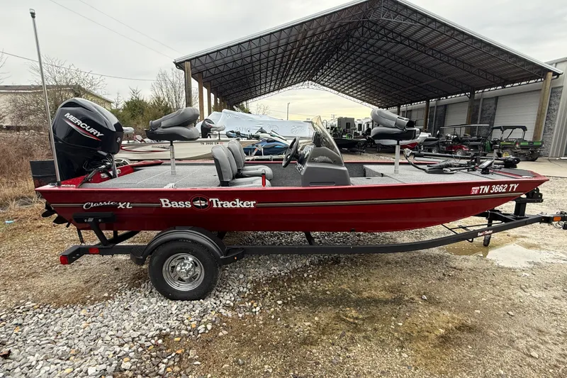 Slide: The Image of 2025 Tracker Bass Tracker Classic XL boat with Mercury engine, parked outdoors. - 7