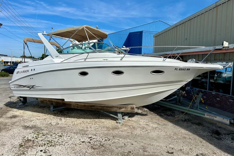 The Image of 2000 Larson 290 Cabrio boat on display outdoors, featuring sleek design and white exterior. - 1