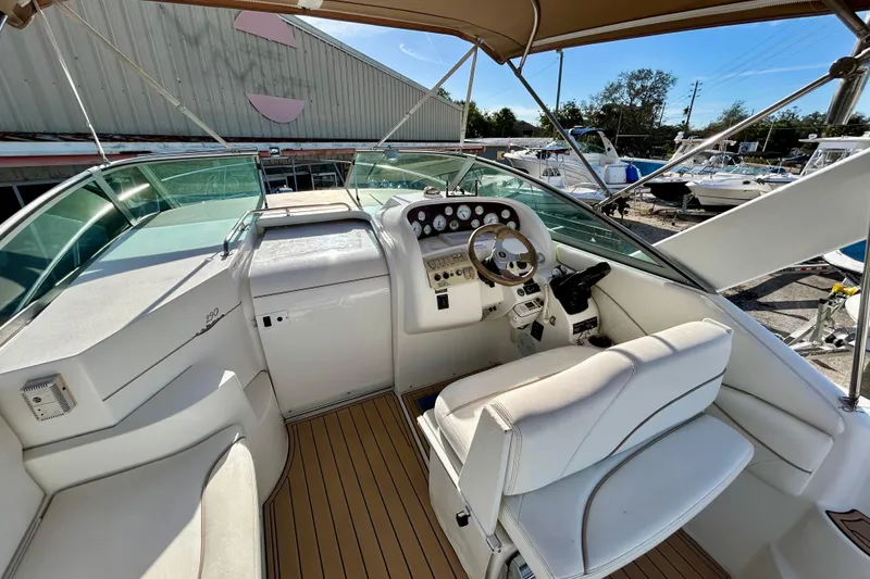 Slide: The Image of 2000 Larson 290 Cabrio boat cockpit with steering wheel and seating, docked outdoors. - 14