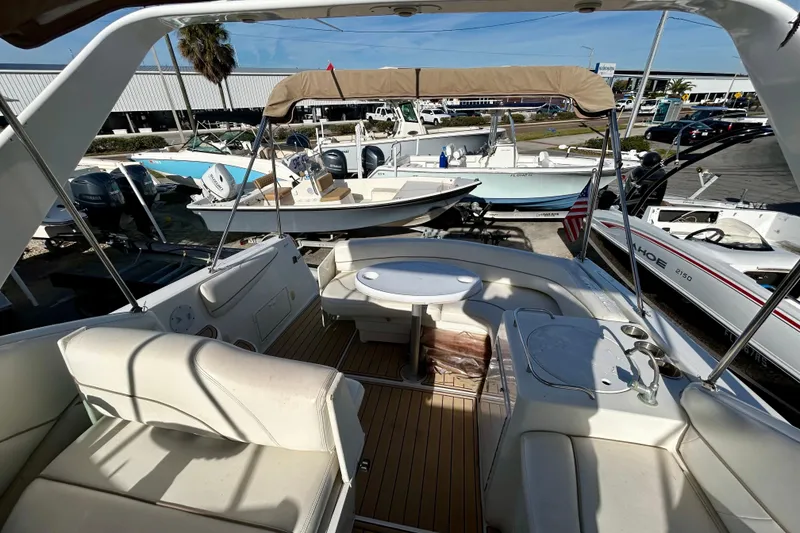 Slide: The Image of 2000 Larson 290 Cabrio boat interior with seating and table, docked among other boats. - 19