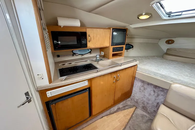 Slide: The Image of Interior of 2000 Larson 290 Cabrio boat with kitchenette and sleeping area. - 4