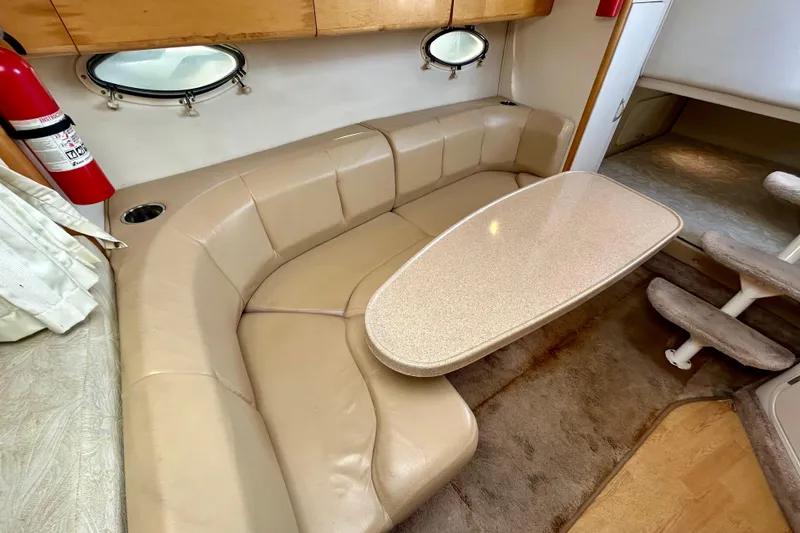Slide: The Image of Interior of 2000 Larson 290 Cabrio boat with beige seating and table. - 5