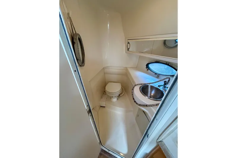 Slide: The Image of Compact bathroom in 2000 Larson 290 Cabrio boat with sink, toilet, and porthole window. - 8