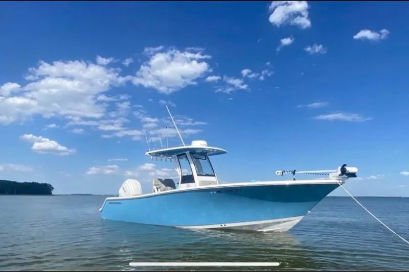 The Image of 2024 Sportsman Open 252 Center Console boat on calm water under blue sky. - 0