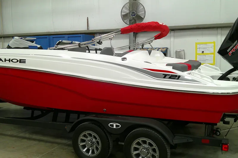 Slide: The Image of 2025 Tahoe T21 boat in a showroom, featuring a sleek red and white design. - 0