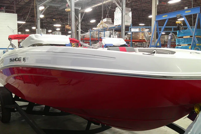 Slide: The Image of 2025 Tahoe T21 boat in a warehouse, featuring a sleek red and white design. - 1