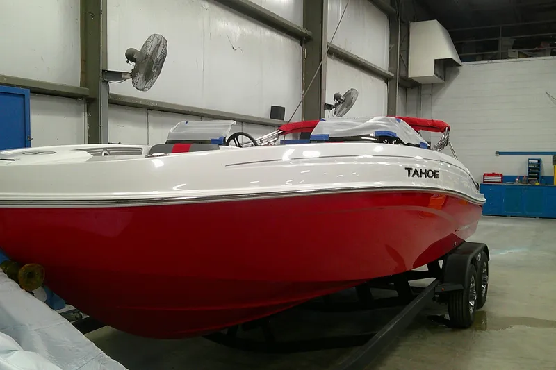 Slide: The Image of 2025 Tahoe T21 boat with red hull in a garage setting. - 2