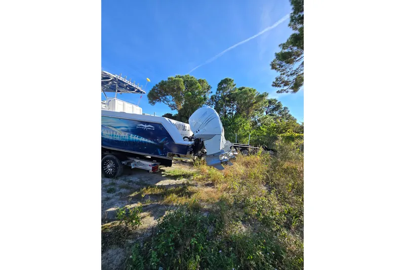 Slide: The Image of 2013 Invincible 42 Open Fisherman boat with outboard motor, parked on grassy terrain. - 5