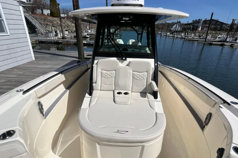 Slide: The Image of 2025 Scout 330 LXF boat with luxurious seating at a marina dock. - 13